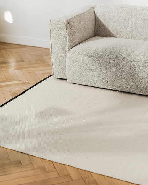 noo.ma handgeweven vloerkleed van Nieuw-Zeelandse wol, beige met Vulcano Black randaccent - rechthoekig, laagpolig 1 cm